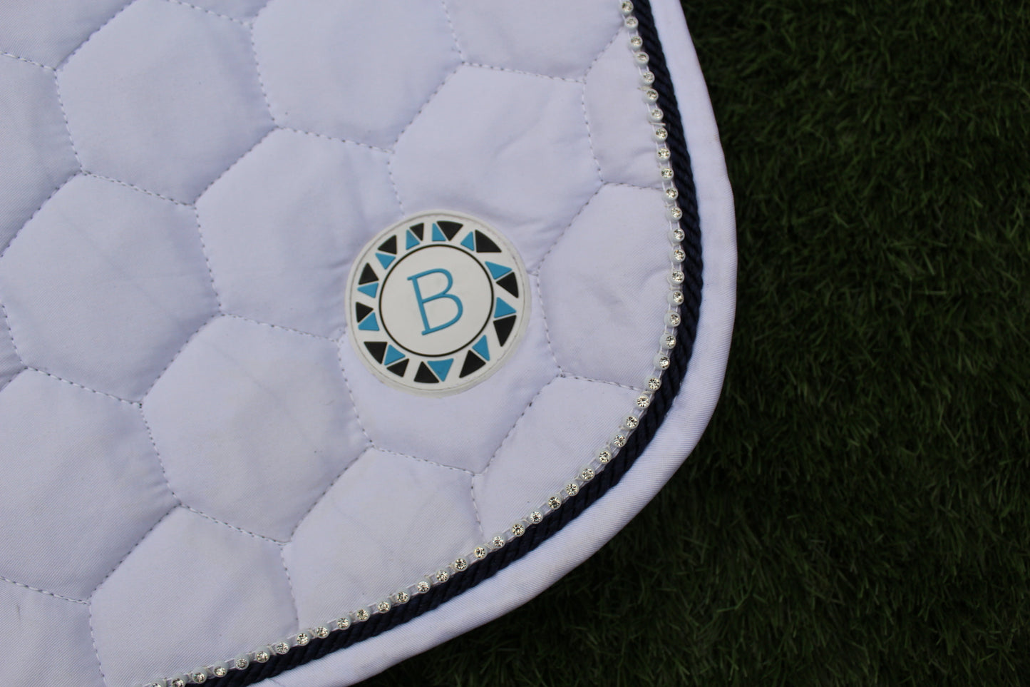 Luxury white cotton competition saddle pad numnah with navy piping and diamontés on it.