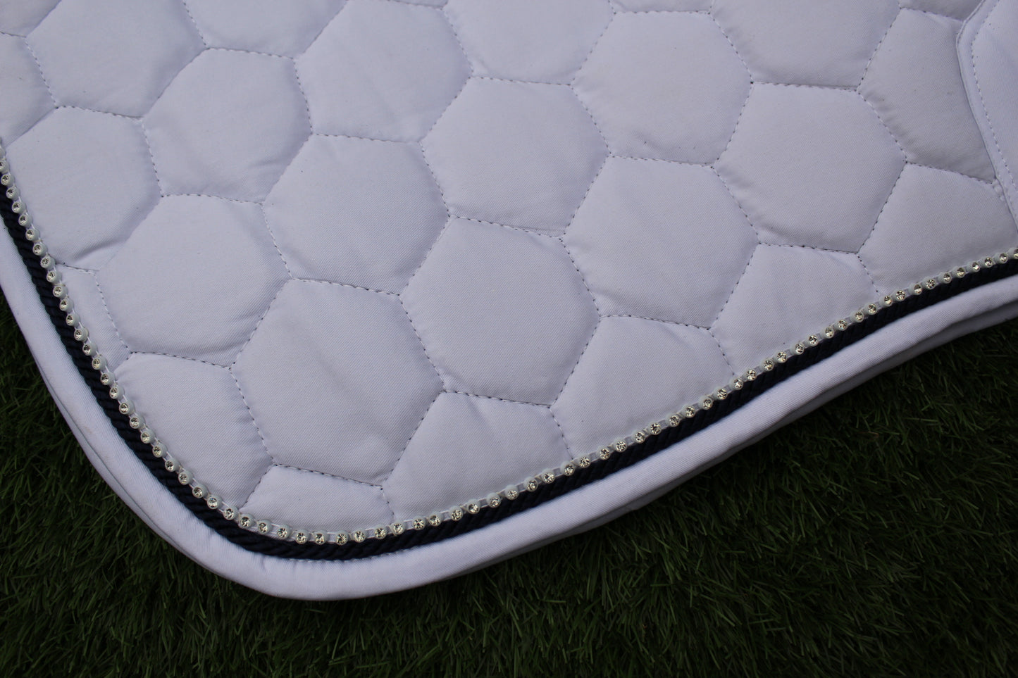 Luxury white cotton competition saddle pad numnah with navy piping and diamontés on it.