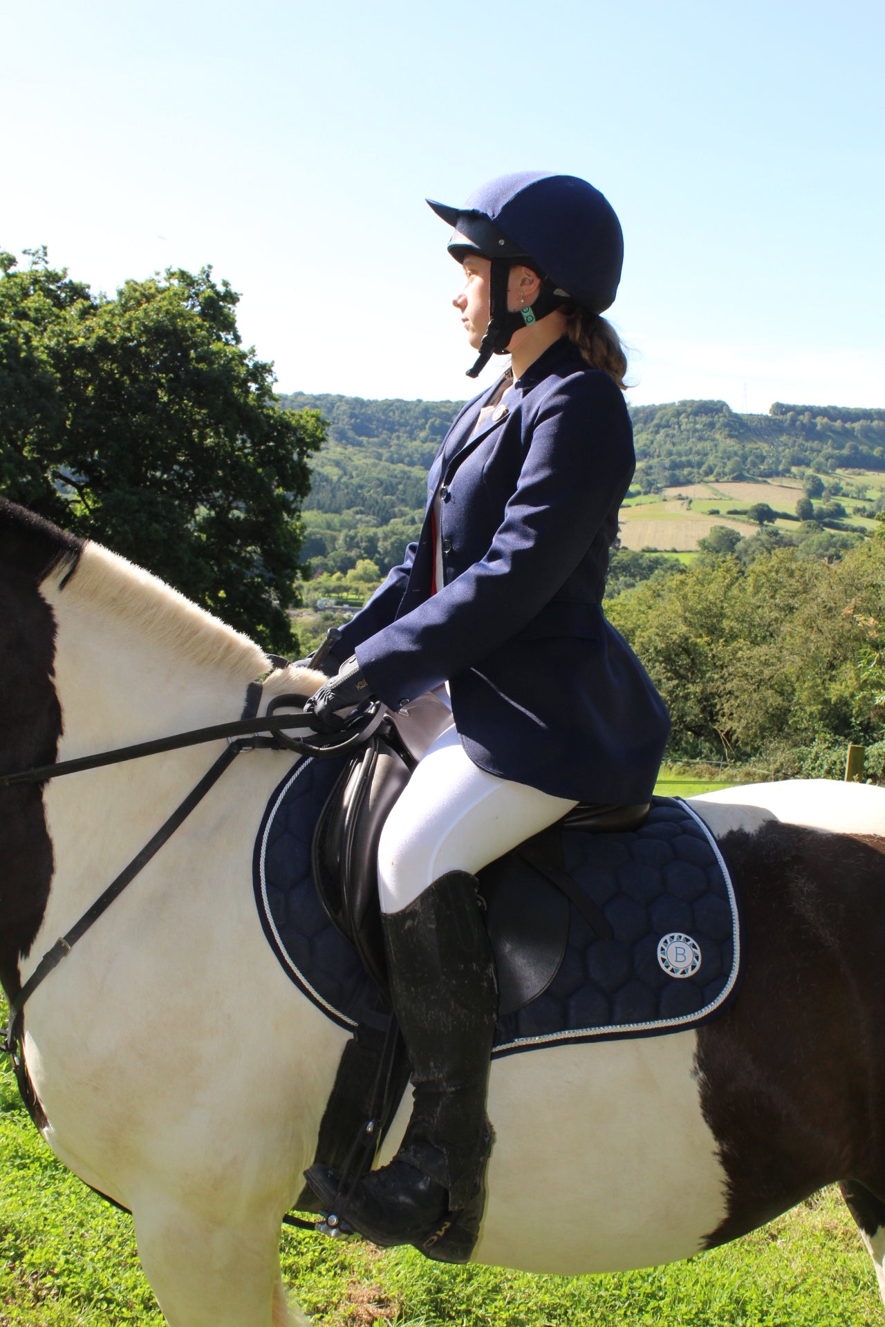 Luxury navy suede competition saddle pad numnah with white piping and diamontés on it.