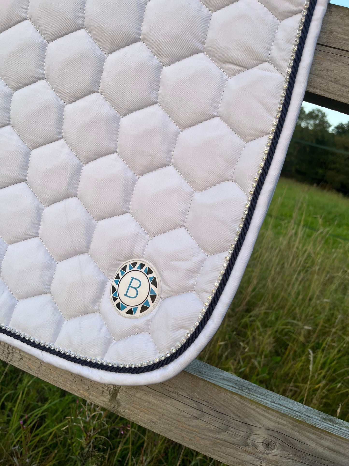 Luxury white cotton competition saddle pad numnah with navy piping and diamontés on it.