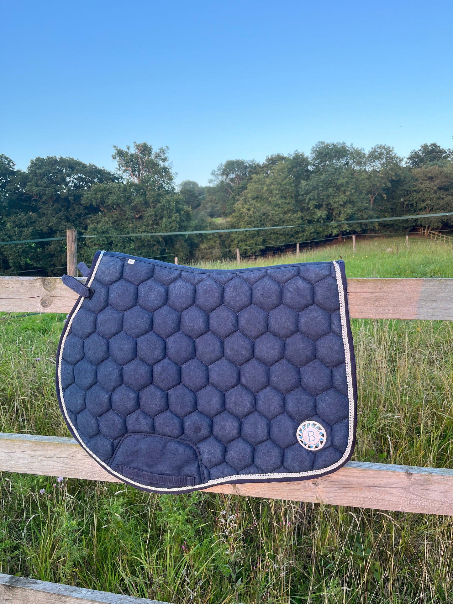 Luxury navy suede competition saddle pad numnah with white piping and diamontés on it.