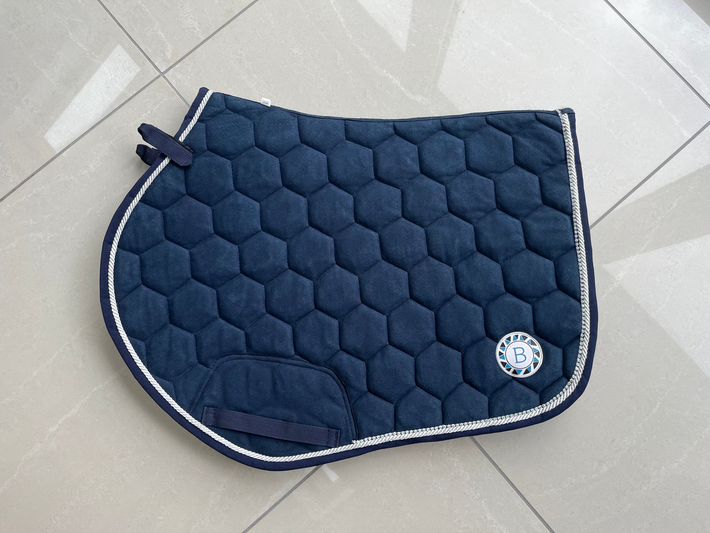 Luxury navy suede competition saddle pad numnah with white piping and diamontés on it.