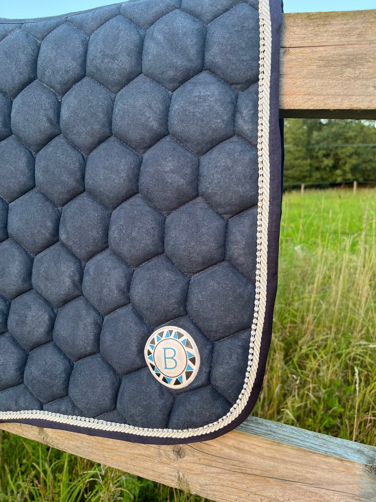 Luxury navy suede competition saddle pad numnah with white piping and diamontés on it.