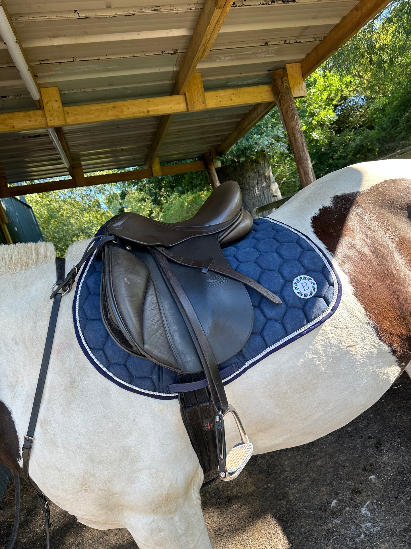 Luxury navy suede competition saddle pad numnah with white piping and diamontés on it.