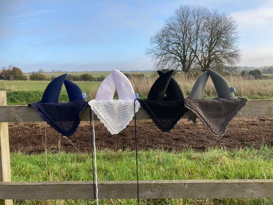 a navy, grey, white and black soundproof ear bonnet on a fence