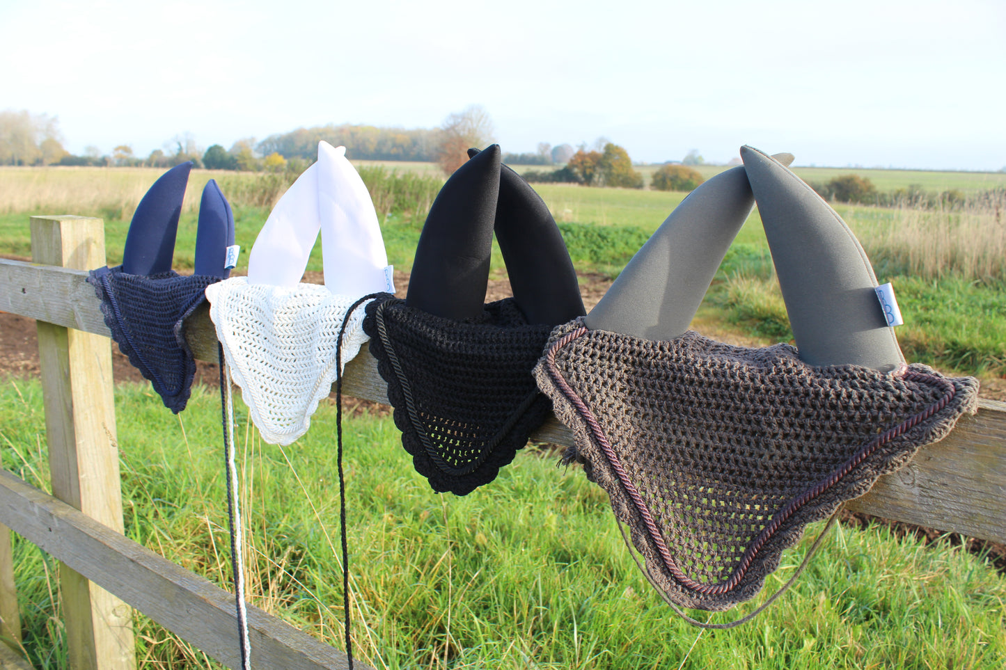 4 soundproof ear bonnets in grey, black, white and navy on a fence