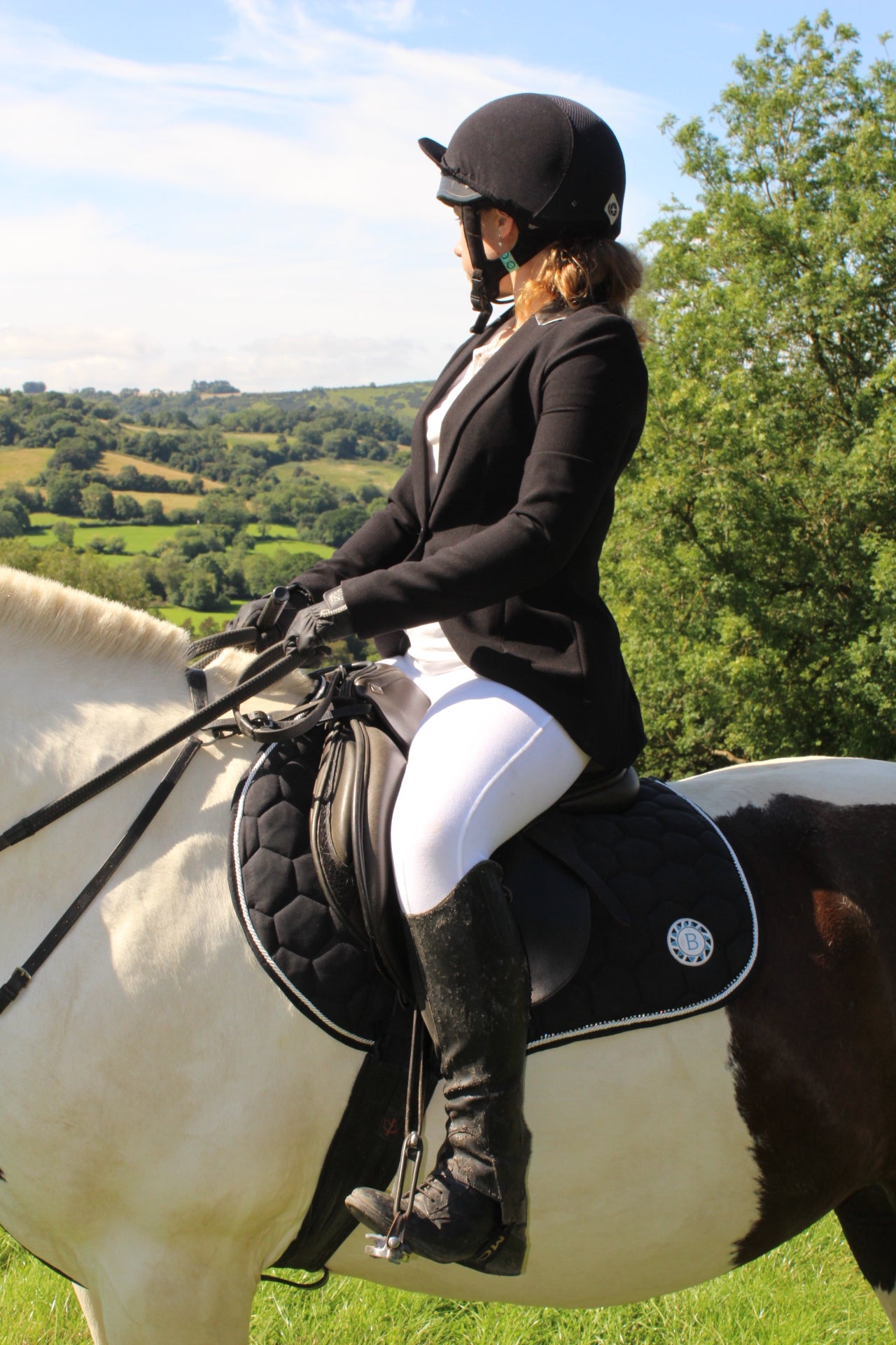 Luxury black suede competition saddle pad numnah with white piping and diamontés on it.
