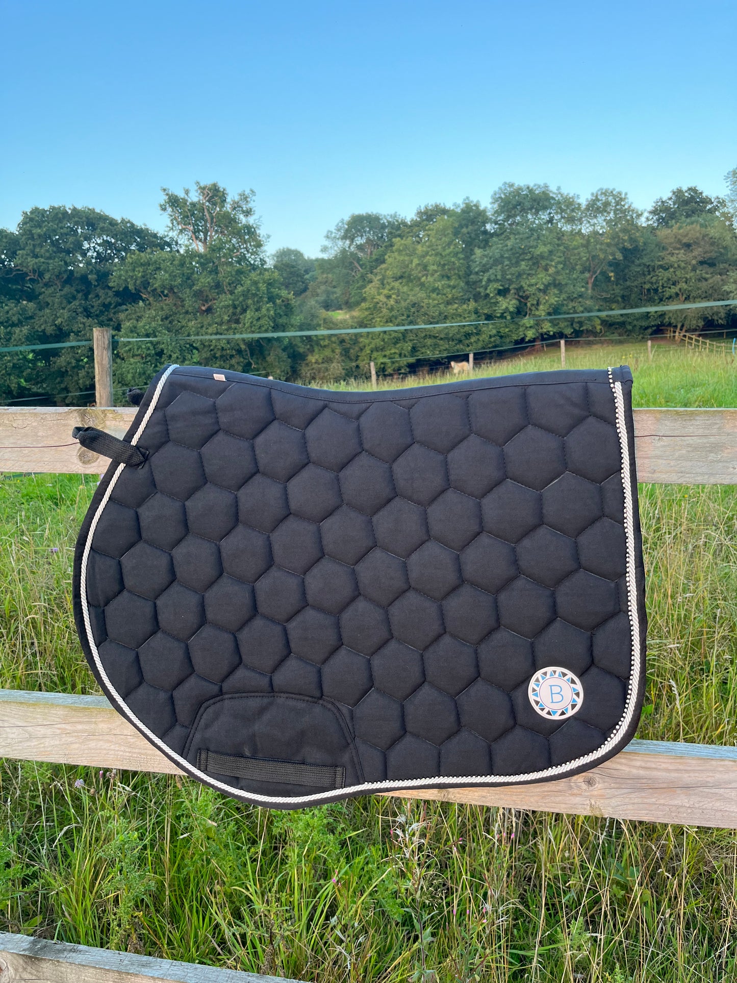 Luxury black suede competition saddle pad numnah with white piping and diamontés on it.