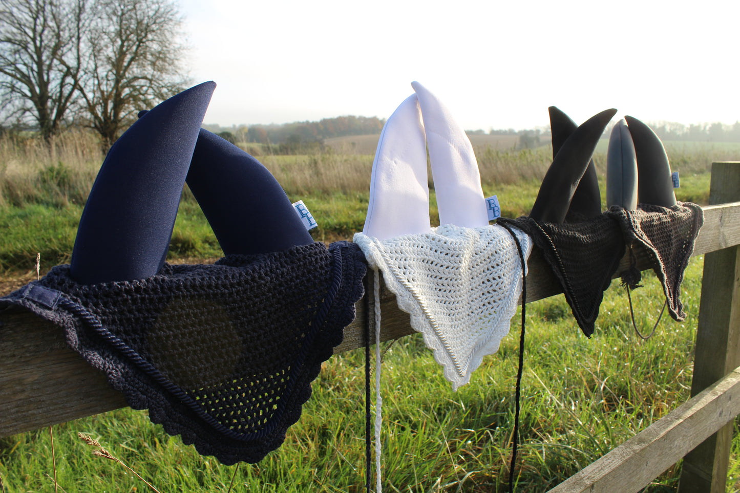 a navy, grey, white and black soundproof ear bonnet on a fence