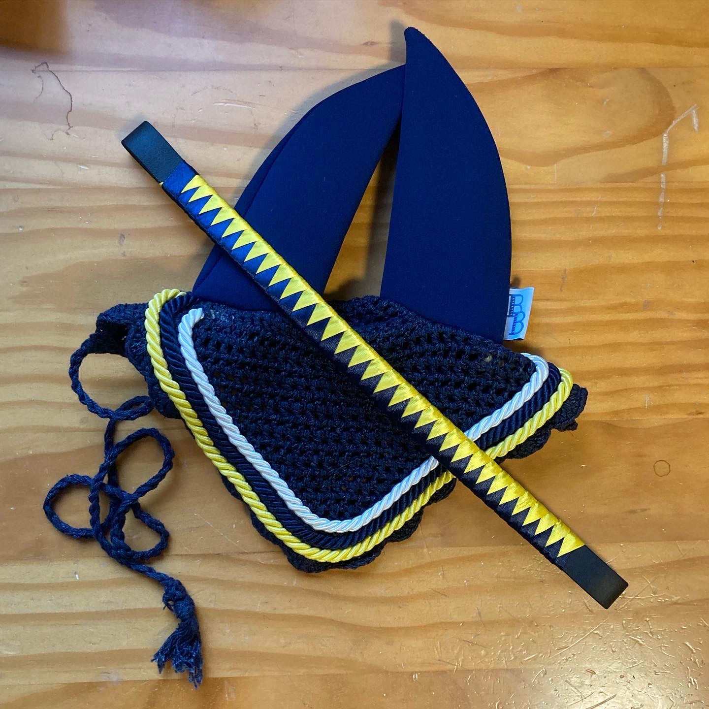 a yellow and navy bespoke browband and a navy soundproof ear bonnet custom made with added white and yellow piping