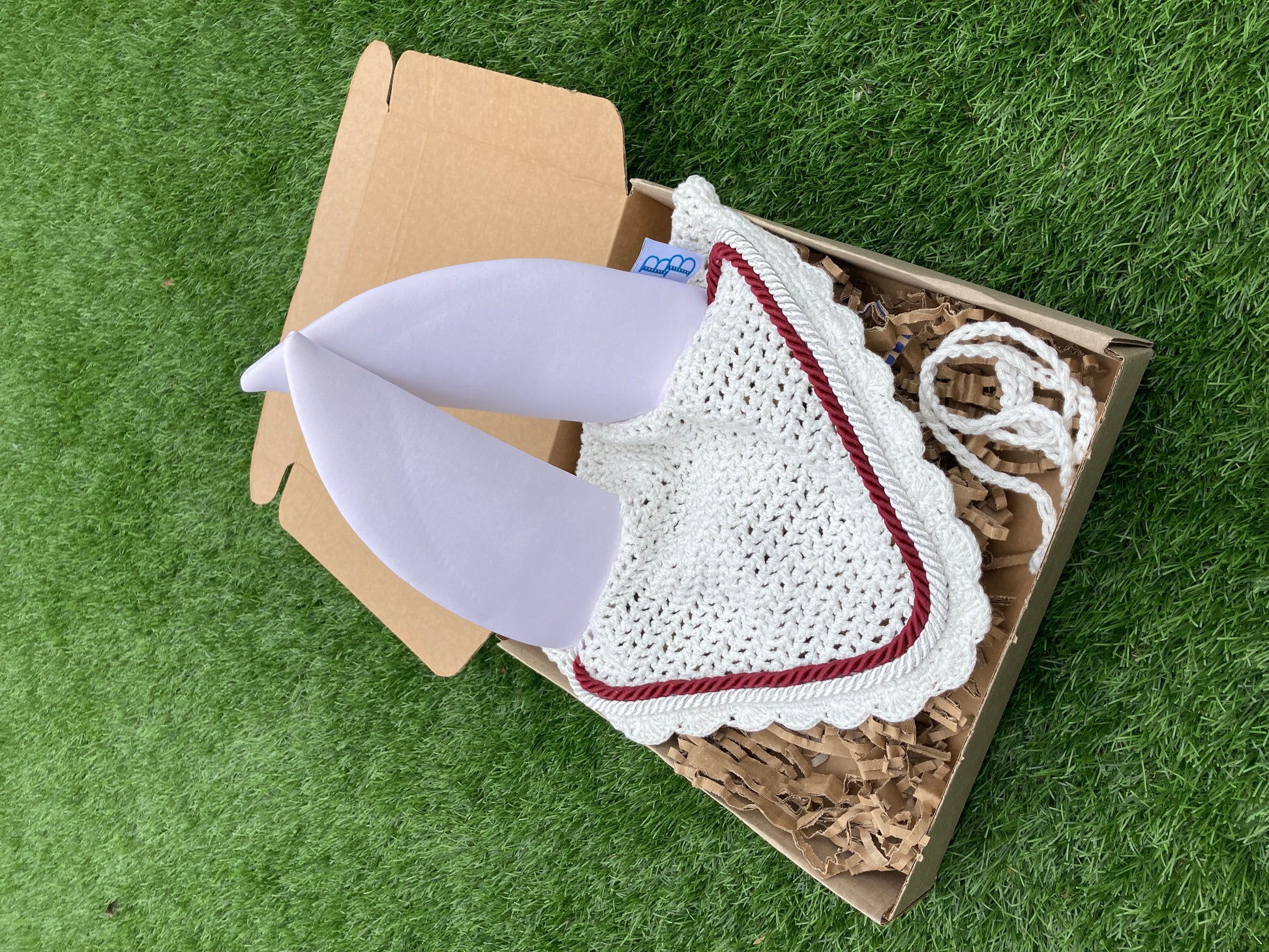a white soundproof ear bonnet customised with burgundy piping